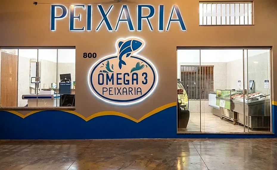 Fachada da Peixaria Ômega 3: letreiro iluminado, vitrines de vidro e balcão refrigerado com produtos à vista
